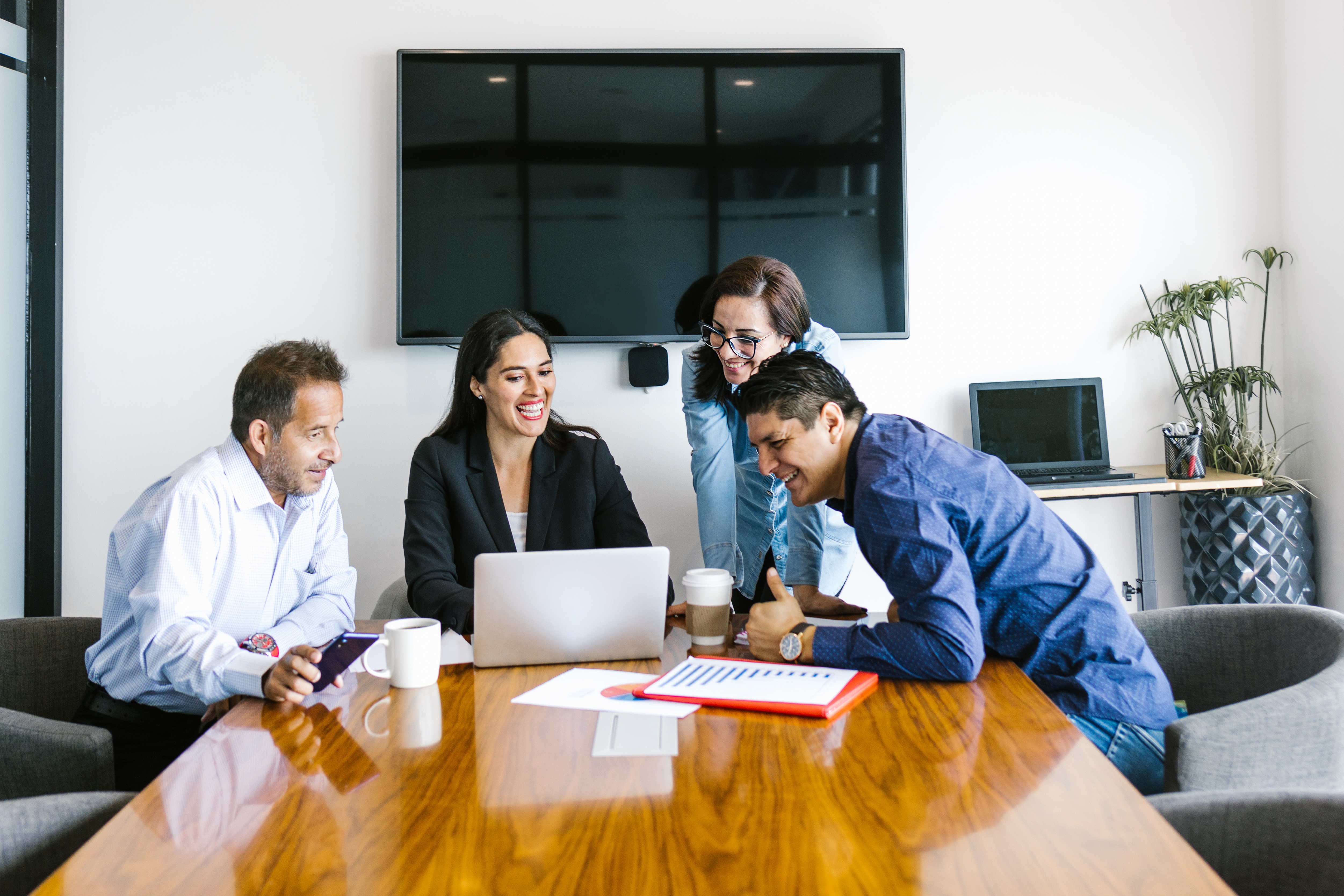 Team of professionals collaborating around a laptop during a meeting in a modern office conference room