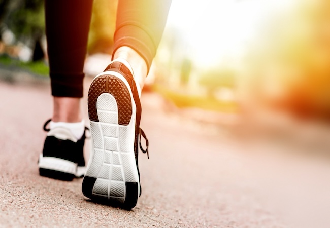 Close-up of a person walking in athletic shoes on a paved path