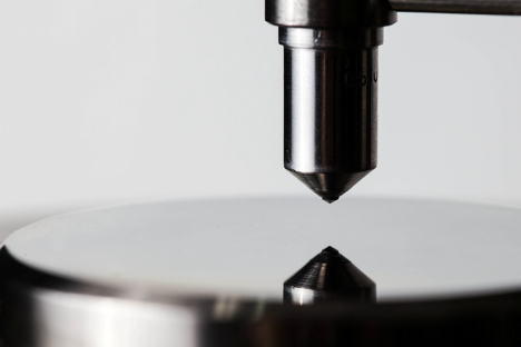 Close-up of a precision testing instrument above a reflective surface.