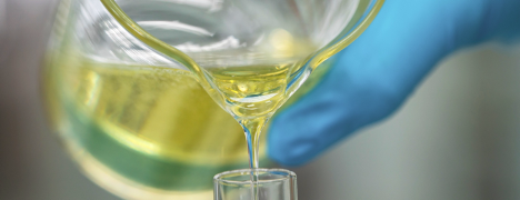 Close-up of yellow liquid being poured into a lab container
