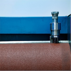 Close-up of industrial machinery over a textured material roll