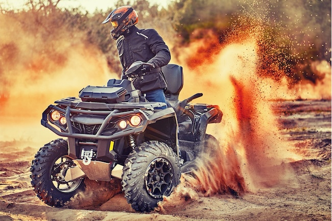 Person riding an ATV through dirt terrain