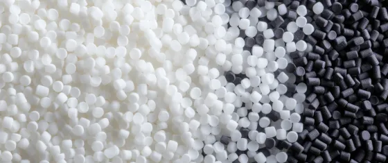 Close-up of white and black plastic polymer pellets used as raw material in manufacturing.